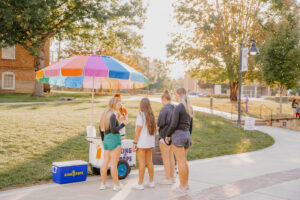 a group of people standing by a sidewalk stand